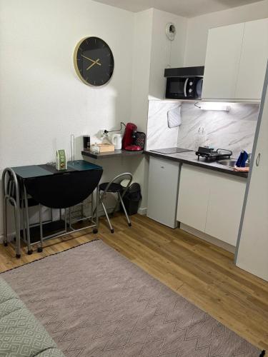 une cuisine avec une table et une horloge au mur dans l'établissement Magnifique studio en bord de mer vue montagne, à Saint-Cyprien