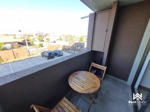 a balcony with a table and a chair and a car at Departamento Corporativo II Talca Las Rastras ' Valles del Country - RENTCOVAC - Factura Inmediata in Talca