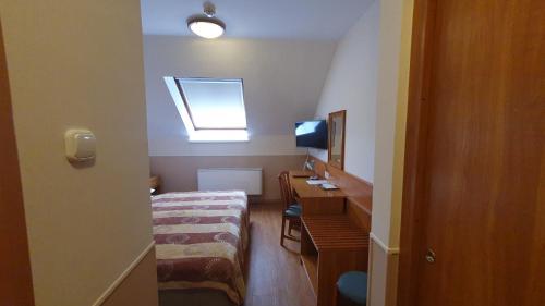 a room with a bed and a desk and a window at Hotel Baross in Győr
