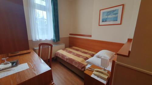 a hotel room with a bed and a desk at Hotel Baross in Győr