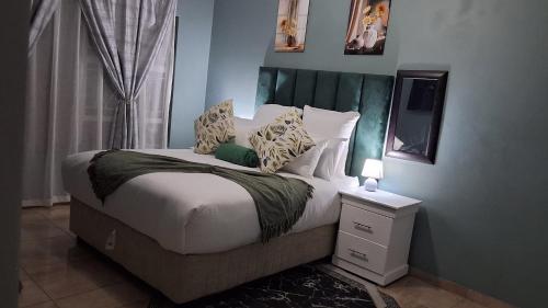 a bedroom with a bed with a green headboard at SIMICON Guesthouse in Witbank