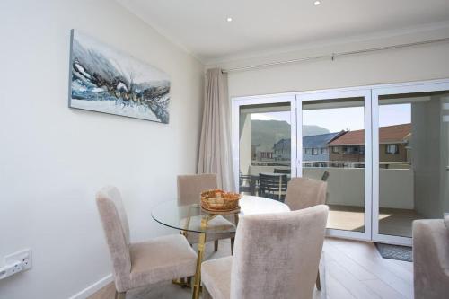 een eetkamer met een glazen tafel en stoelen bij Comfort & Style apartment 200m to beach with parking in Kaapstad