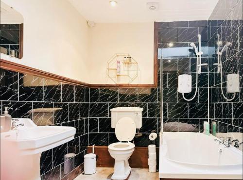 a bathroom with a toilet and a sink and a tub at Stacey's 4 Bedroom House in Pontypool in Pontypool