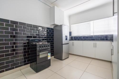 cocina con azulejos negros en la pared y fogones en Safi Luxury Apartment 6 - 2 bedroom, en East London