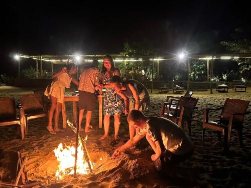 a group of people standing around a fire at Blue Waters in Arugam Bay