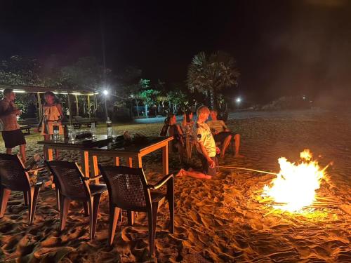 a group of people sitting around a fire on a beach at Blue Waters in Arugam Bay