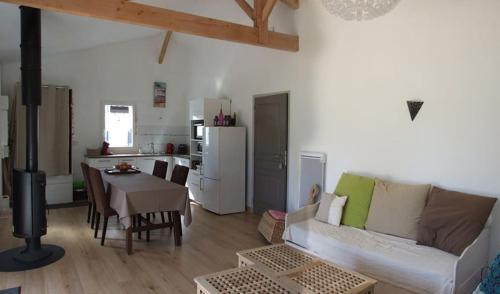 un salon avec un canapé et une table et une cuisine dans l'établissement Le bois Flotée Cottage avec jardin, Lac 6 min, Océan plage 15 min, à Hourtin