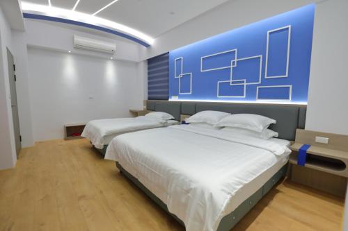Dos camas en una habitación con una pared azul. en 穗美人民宿, en Ruisui
