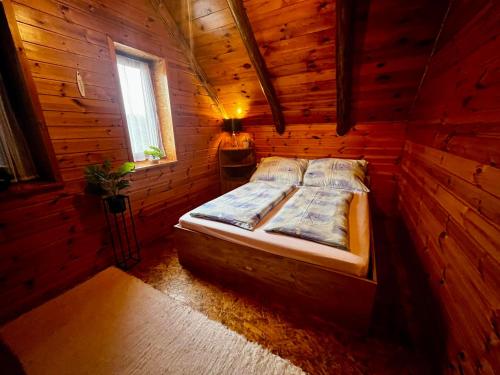 a bedroom with a bed in a wooden room at Onyx Vendégház - vízparti nyaraló in Gyomaendrőd