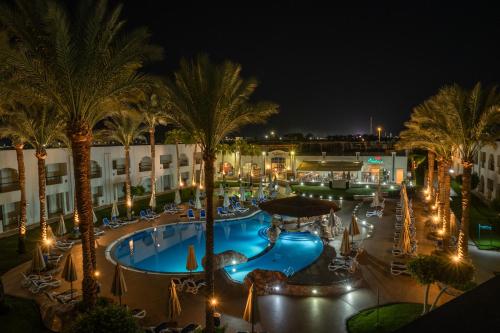 an outdoor swimming pool at night with palm trees at Xperience St. George Sharm El Sheikh in Sharm El Sheikh