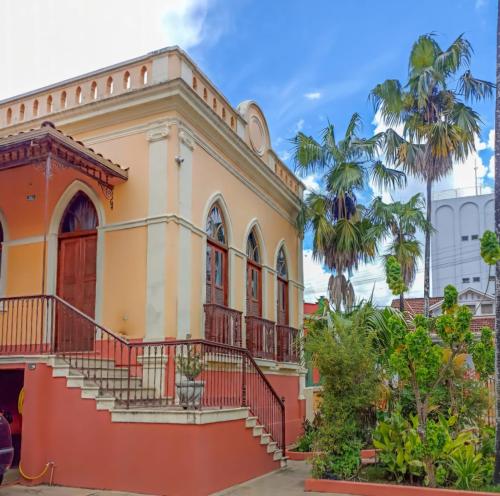 an old building in the city with palm trees at Pousada Estação do Trem in São João del Rei