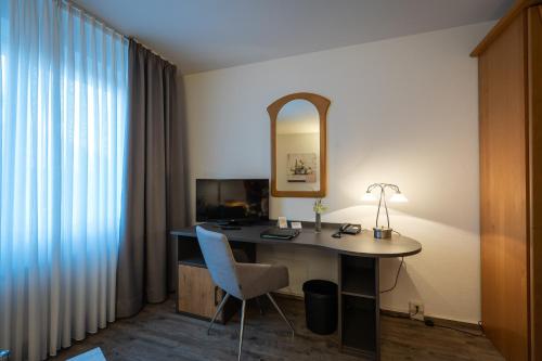 a room with a desk with a chair and a mirror at Hotel Pfälzer Hof GmbH in Braunschweig