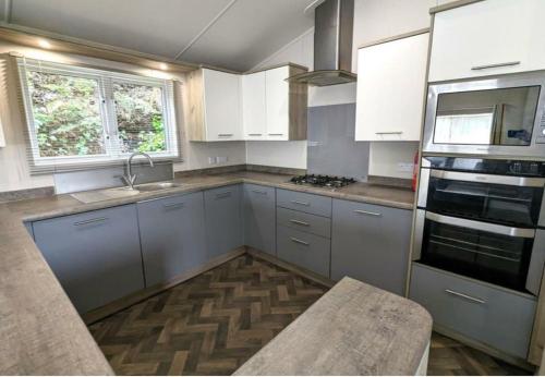 a kitchen with white cabinets and a sink at Yellow Bush Lodge in Haven Street