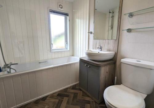 a bathroom with a toilet and a sink and a tub at Yellow Bush Lodge in Haven Street