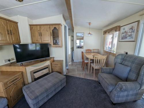 a living room with a couch and a tv and a table at Highland getaway in kingussie golf club in Kingussie