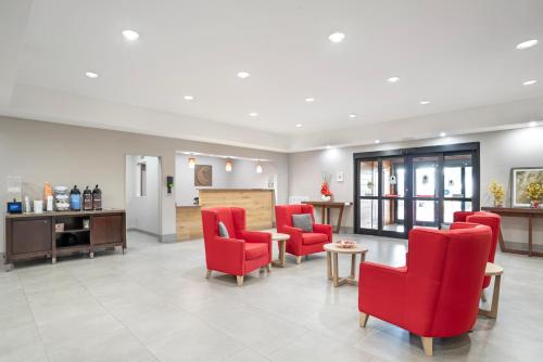 a waiting room with red chairs and a table at Comfort Inn & Suites in Slidell