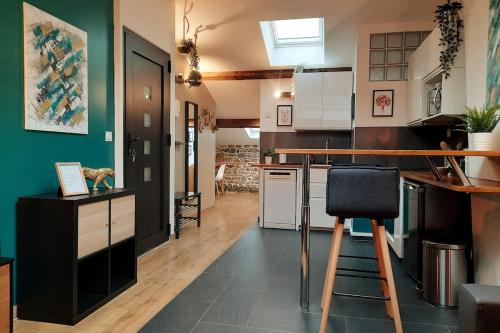 a kitchen with green walls and a bar with a stool at Grand appartement proche métro avec place de parking in Lyon