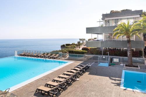 une piscine avec des chaises longues et l'océan dans l'établissement LA RESIDENCE COSTA PLANA, Appt 204, VUE SUR LA MER, à Cap d'Ail
