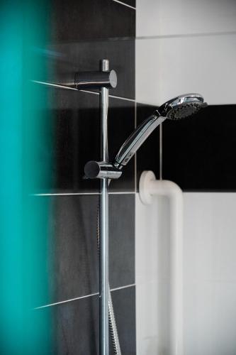 a shower head in a bathroom with black tiles at Centre Jean XXIII in Annecy