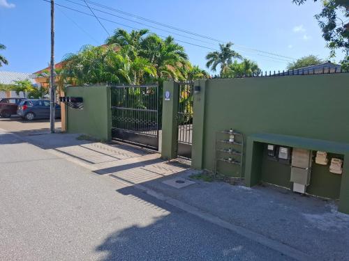 a green fence with a gate on the side of a street at Tropical Palm Retreat in Willemstad