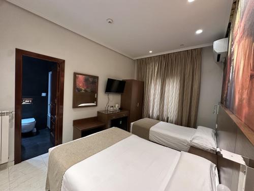 Una habitación de hotel con dos camas y un baño. en Hostal Atocha Almudena Martín, en Madrid