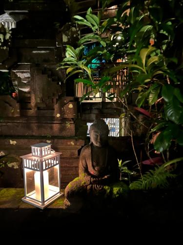 a small statue sitting next to a lit lantern at The Nest in Ubud, Bembengan Cottage in Ubud