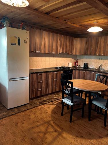 a kitchen with a table and a white refrigerator at Sodyba Pas Juzi in Alanta