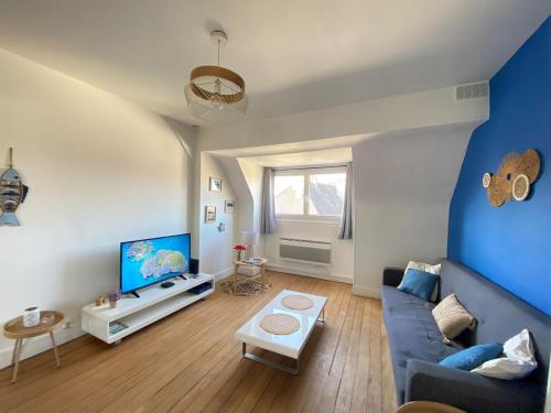 un salon avec un canapé bleu et une télévision dans l'établissement Au cocon bleu, à Calais