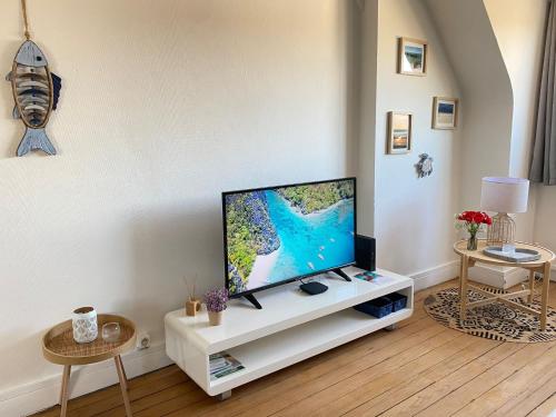 un salon avec une télévision à écran plat sur un meuble blanc dans l'établissement Au cocon bleu, à Calais
