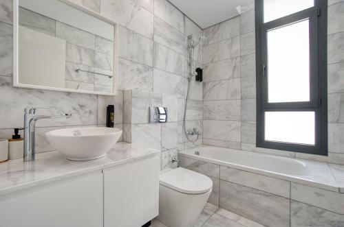 a white bathroom with a sink and a toilet and a tub at Oasis Villa 3 in Khlorakas