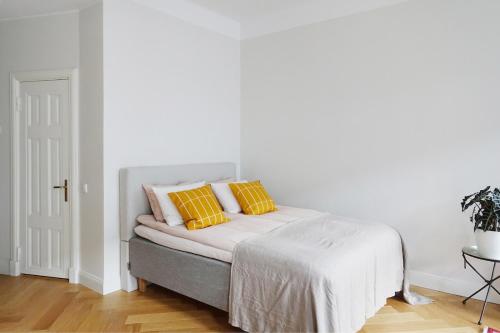 a white bedroom with a bed with two yellow pillows at Stylish Design Studio Next to The Parliament House in Helsinki