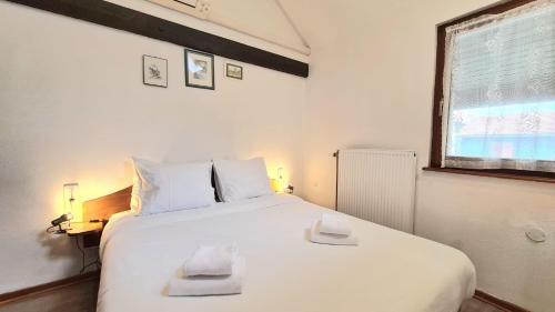 une chambre avec un lit blanc avec deux serviettes dessus dans l'établissement Gîte et Chambres d'hôtes, l'Erable, à Beblenheim