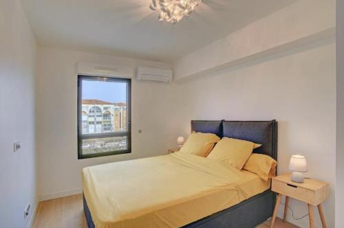 une chambre avec un lit, une fenêtre et un lustre dans l'établissement Le Royal Mer -Clim et Parking-, à Sète