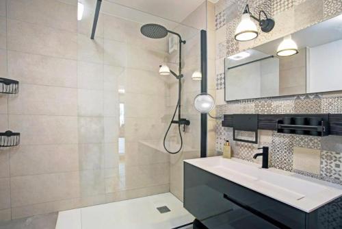 une salle de bain avec un lavabo, une douche et un miroir dans l'établissement Le Royal Mer -Clim et Parking-, à Sète