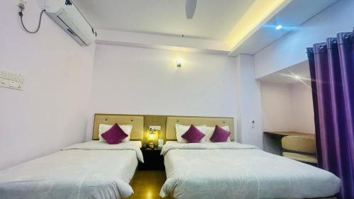 two beds in a room with white walls and purple curtains at Best Southern Hotel in Kuākāta