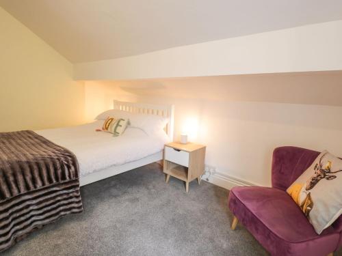 Un pequeño dormitorio con una cama y una silla. en 21 Taliesin Street, en Llandudno