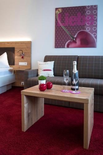 a living room with a couch and a table with wine glasses at Hotel Garni Schmieder’s Ochsen in Seelbach
