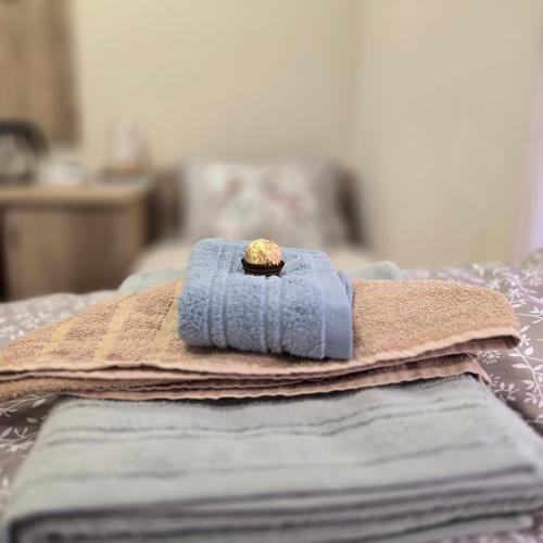 a pile of towels on a bed with a cookie on top at MA DONNA rooms in Floreşti