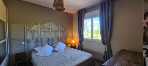 une chambre avec un lit avec des oreillers blancs et une fenêtre dans l'établissement Gîte Bevennes maison individuelle au calme, à Ruoms