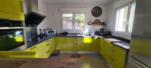 une cuisine avec des armoires jaunes et un comptoir jaune dans l'établissement Gîte Bevennes maison individuelle au calme, à Ruoms