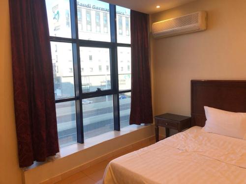 a bedroom with a bed and a large window at شقق أروع القصور للشقق المخدومة in Abha
