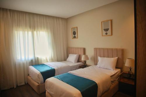 ein Hotelzimmer mit zwei Betten und einem Fenster in der Unterkunft Settle Inn Cairo Festival City Villa in Kairo
