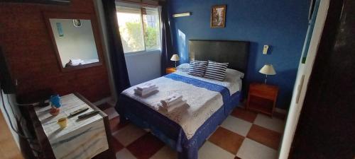 a blue bedroom with a bed and a mirror at Casa Acacias in Sierra de la Ventana