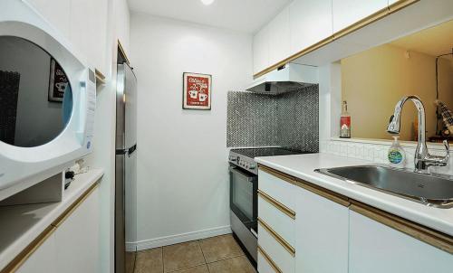 a white kitchen with a sink and a microwave at Hameau 28-51 Studio in Stoneham