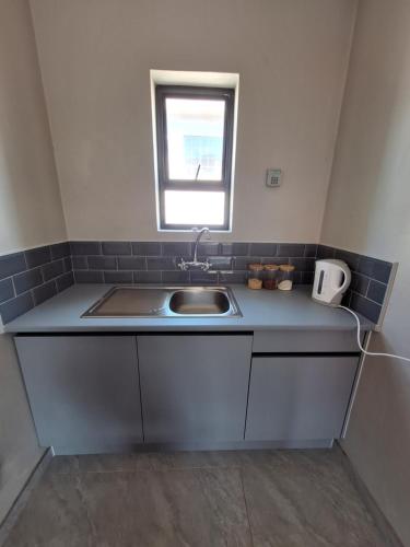 Una pequeña cocina con fregadero y ventana. en Eazy Rest, en Gqeberha