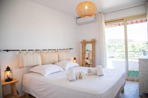 une chambre avec un grand lit blanc avec des serviettes dessus dans l'établissement Beautiful Apartment with Terrace AC and PARKING, au Cannet