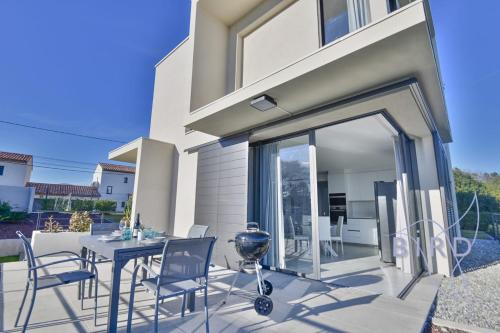 un patio avec une table et des chaises devant une maison dans l'établissement Contemporary Villa Pool and Sea View, à Cagnes-sur-Mer