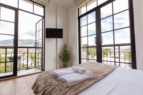 una camera da letto con ampie finestre e un letto con asciugamani di Mumbai Corner View Studio a Quito