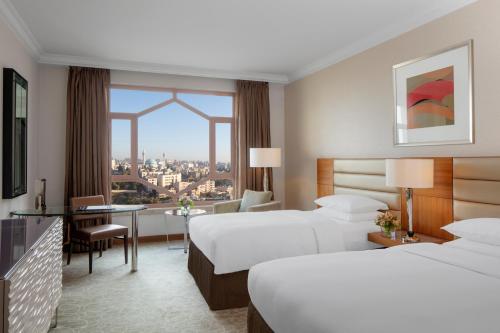 a hotel room with two beds and a desk at Grand Hyatt Amman in Amman