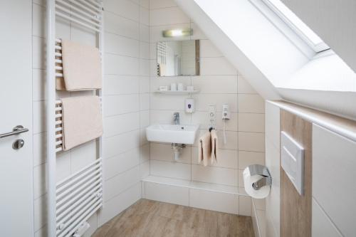 a white bathroom with a sink and a mirror at Pension Sonnenstrand in Norden